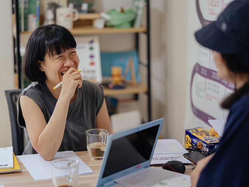 책상에 앉아 활짝 웃고 있는 여성